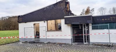 Brandbesch&auml;digtes Geb&auml;ude mit verru&szlig;tem Dach und zerst&ouml;rten Fenstern, abgesperrt mit rot-wei&szlig;em Flatterband.