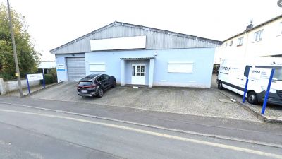 Blaues PSM Gewerbegeb&auml;ude in Friedrichsdorf mit Rolltor und Eingangst&uuml;r, davor geparktes Auto und wei&szlig;er Lieferwagen mit PSM-Beschriftung.