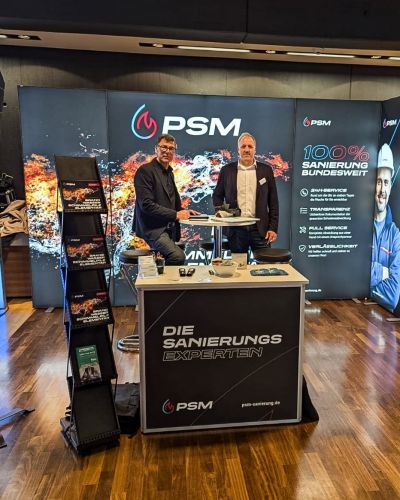 Messestand von PSM GmbH mit zwei M&auml;nnern, Bannern zur Sanierung und einem Bildschirm im Hintergrund.